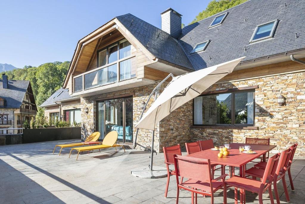a patio with a table and chairs and an umbrella at Luderna - Casa con jardín Montcorbison in Vielha