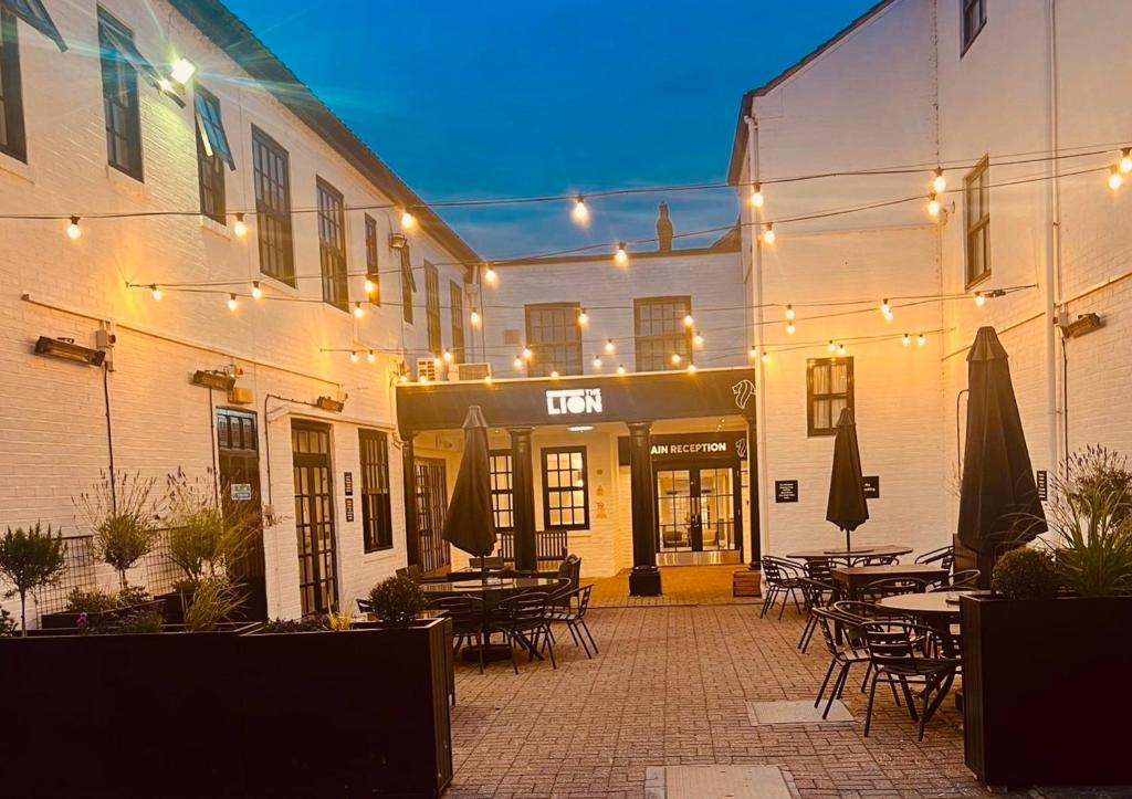 a patio with tables and umbrellas in front of a building at Lion Hotel in Worksop