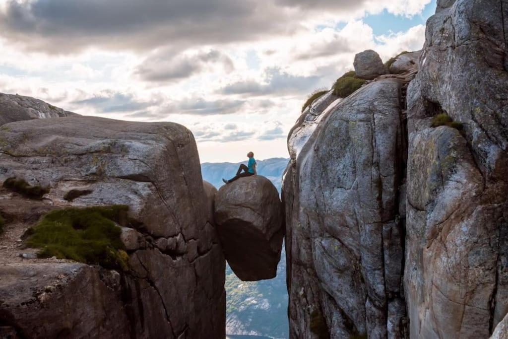 una persona sentada en una roca en la cima de una montaña en Sjarmerende leilighet i Sirdal, en Haugen