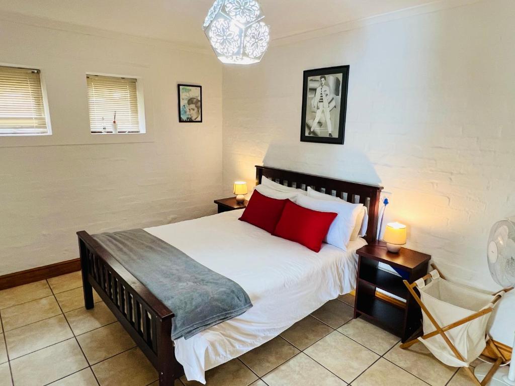 1 dormitorio con 1 cama grande con almohadas rojas en Westford birds nest, en Knysna