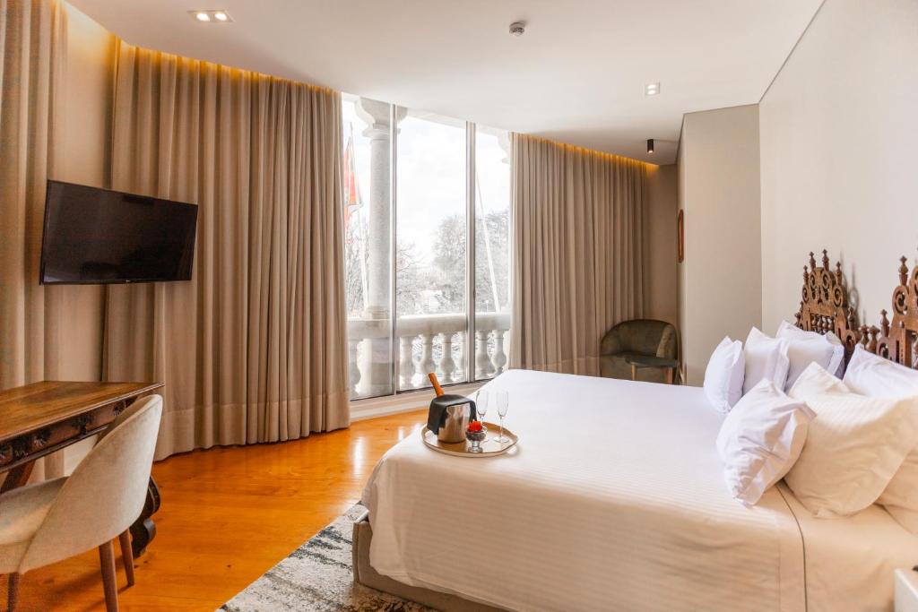 een hotelkamer met een groot wit bed en een bureau bij Avenida Boutique Hotel in Viseu