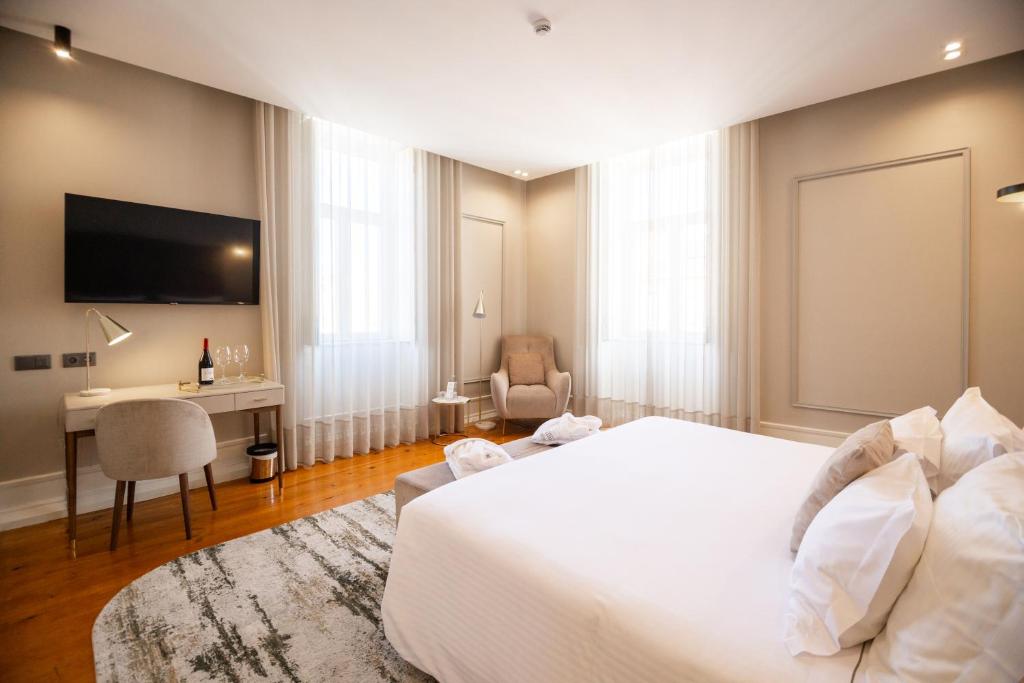 a bedroom with a large white bed and a desk at Avenida Boutique Hotel in Viseu