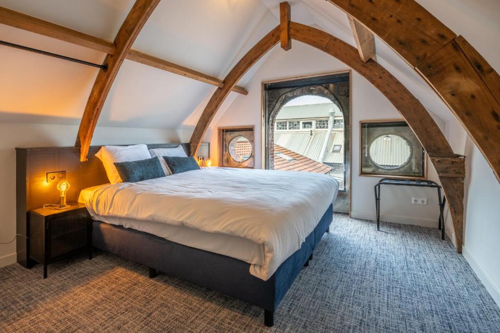 una camera da letto con un grande letto in mansarda di Grapèlli Boutique Hotel ad Alkmaar