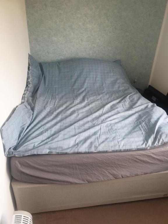 a bed with a blue pillow on top of it at Greys room share in Warrington