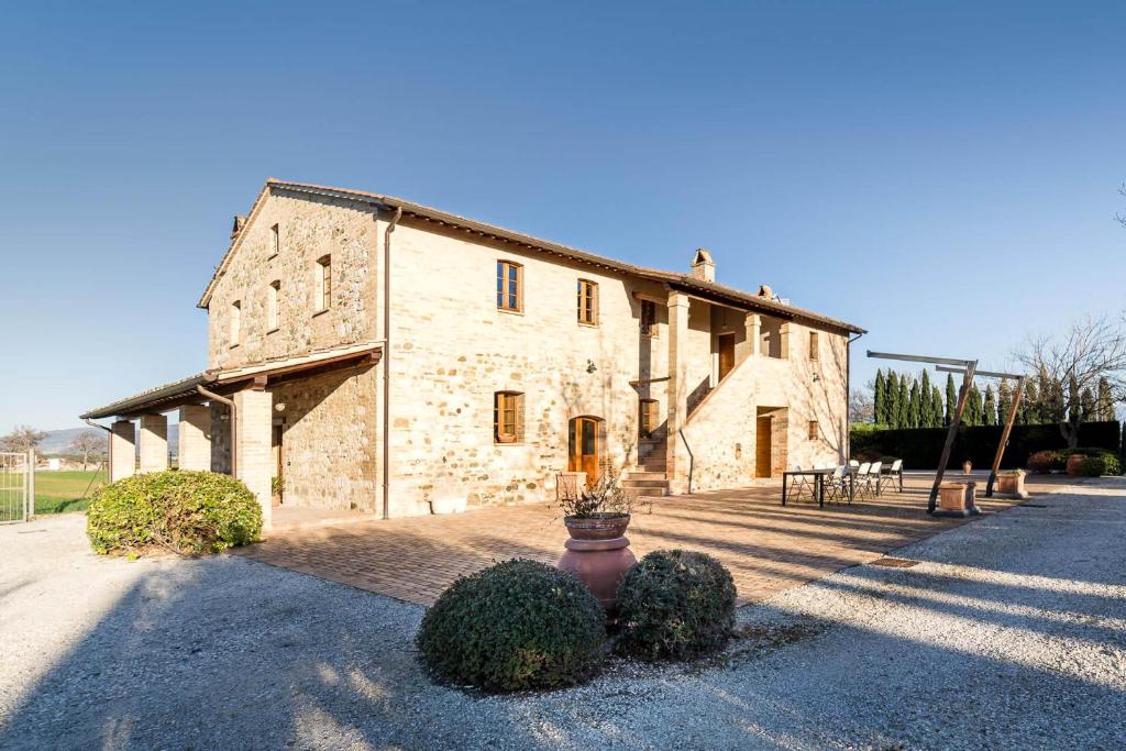a large stone building with bushes in front of it at Agriturismo - La Campagna di San Francesco in Tordandrea
