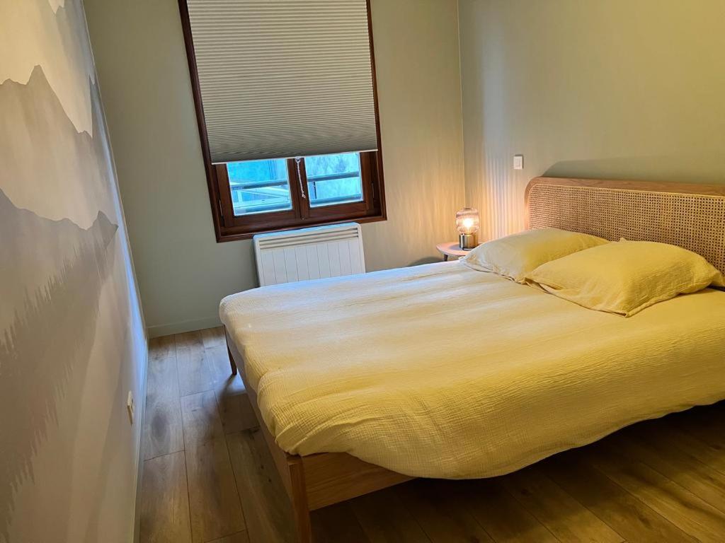 a bedroom with a large bed with yellow sheets and a window at La Perle en ville t2 hyper centre in Thonon-les-Bains