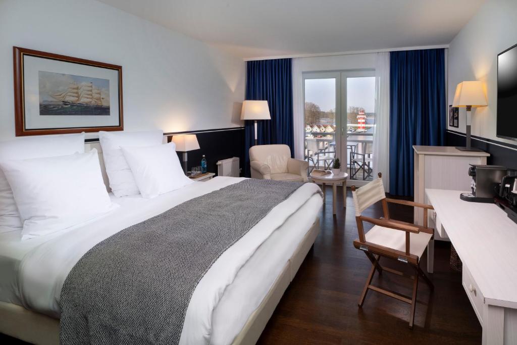 ein Hotelzimmer mit einem großen Bett und einem Schreibtisch in der Unterkunft Precise Resort Hafendorf Rheinsberg in Rheinsberg
