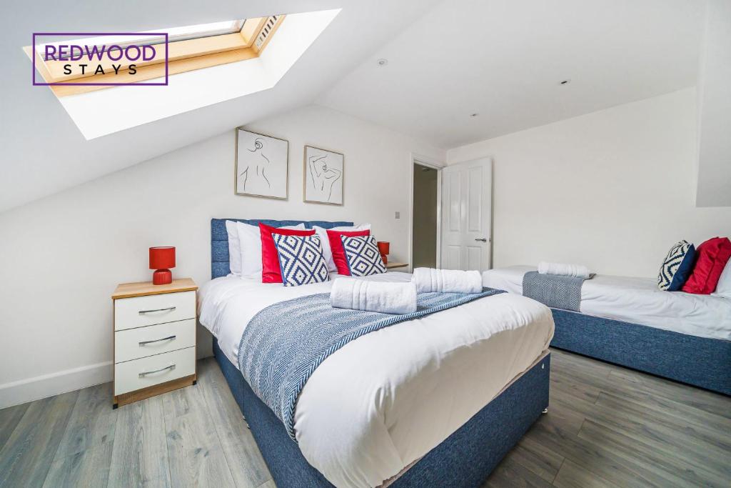 a bedroom with two beds with red and blue pillows at Centrally Located Serviced Apartments in Aldershot Town Centre, Free WiFi By Redwood Stays in Aldershot