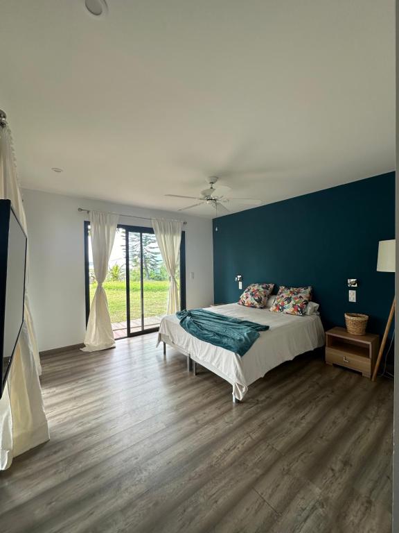- une chambre avec un lit et un mur bleu dans l'établissement Grande Villa Familiale avec piscine et Accès Privé à la Plage, à Païta