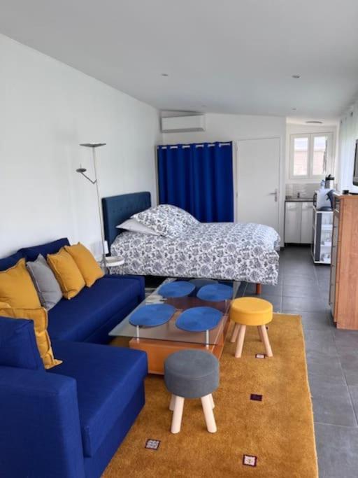 een woonkamer met een blauwe bank en een bed bij Ma chaumière santenoise in Santeny
