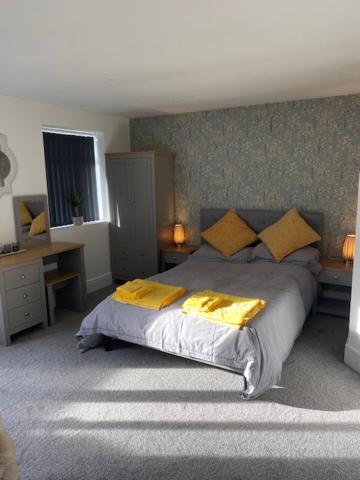a bedroom with a bed with two yellow pillows at The Snug at Parley in West Parley