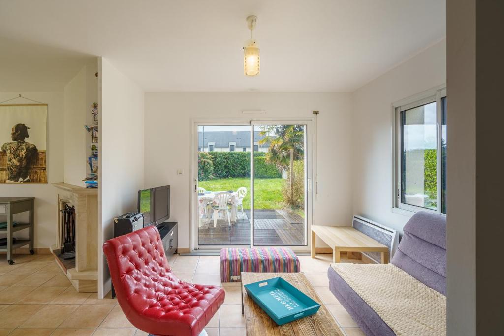 een woonkamer met een rode stoel en een bank bij Ti Louarn - Maison à 2 km de la plage in Fouesnant