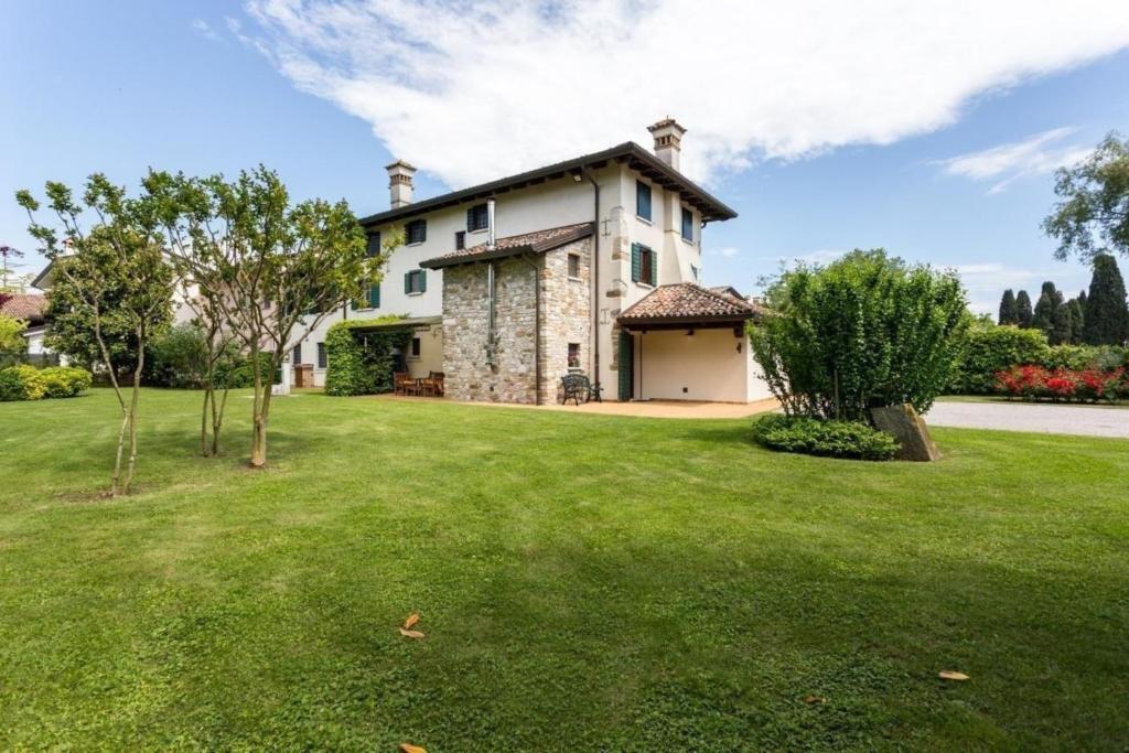 een huis met een grote tuin met groen gras bij Ferienhaus in Aquileia mit Großem Garten in Aquiléia