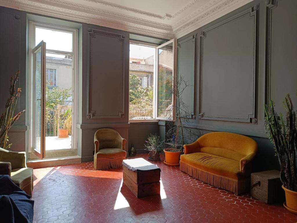 a living room with a couch and two chairs and windows at Chambre d'hôtes 2 pers - Maison partagée avec jardin et terrasse près de la Friche de la Belle de mai in Marseille