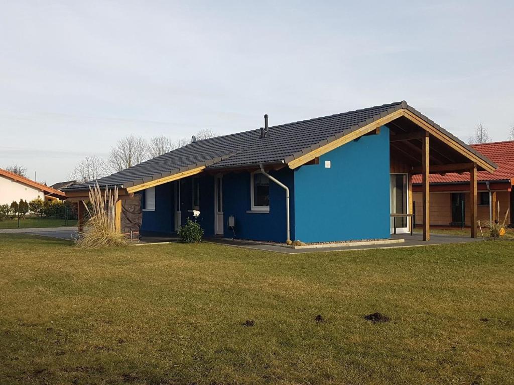 ein blaues Haus mit schwarzem Dach auf einem Hof in der Unterkunft Gemütliches Ferienhaus in Großwürden mit Grill, Garten und Terrasse in Butjadingen
