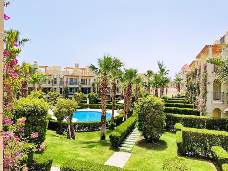 un jardín con piscina, palmeras y arbustos en Stunning Pool View 1bed Private Beach Clubs, Veranda Sahl Hasheesh, en Hurghada