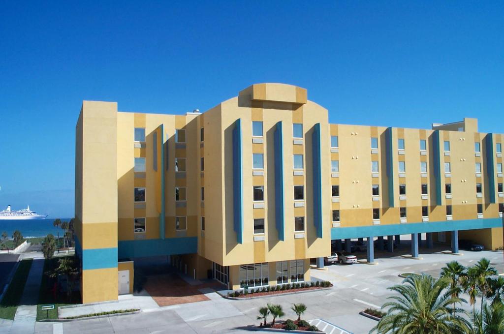 a large white building with a blue sky at Cocoa Beach Suites Hotel in Cocoa Beach