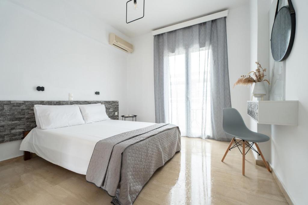 a white bedroom with a bed and a chair at Bellisimo studios in Zakynthos Town