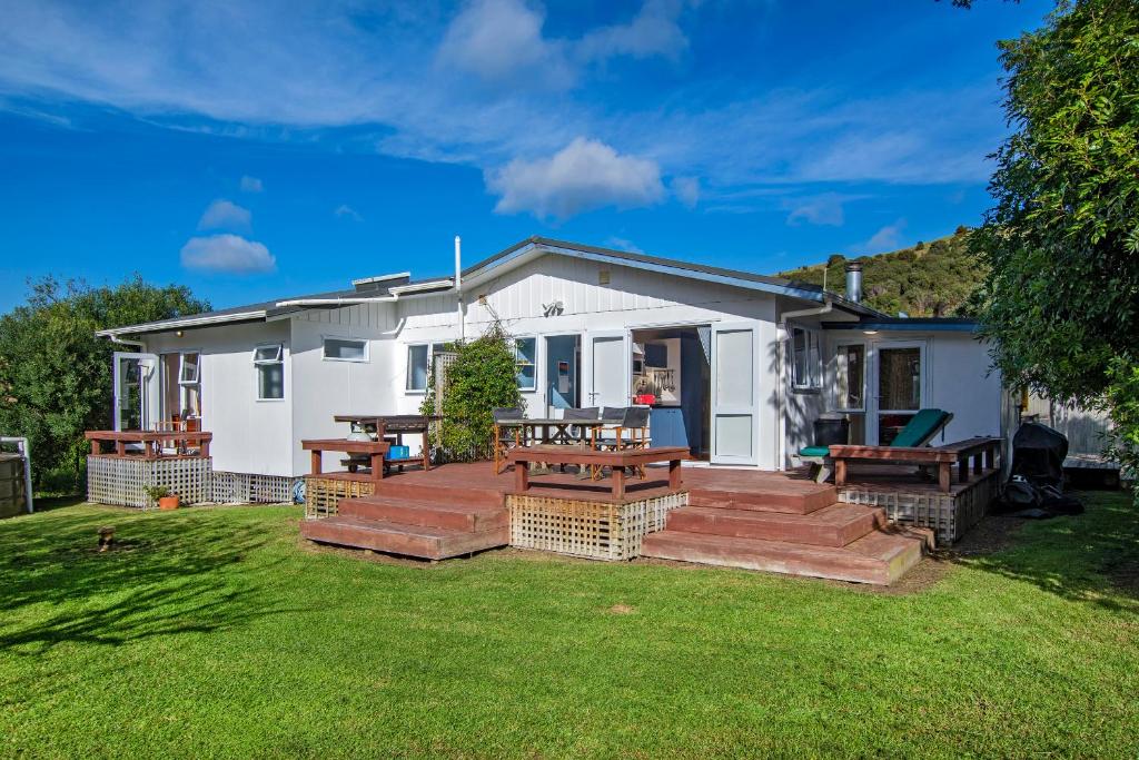 una casa con tavolo da picnic e panchine nel cortile di Teal Bay Treasure - Teal Bay Holiday Home a Whangaruru North