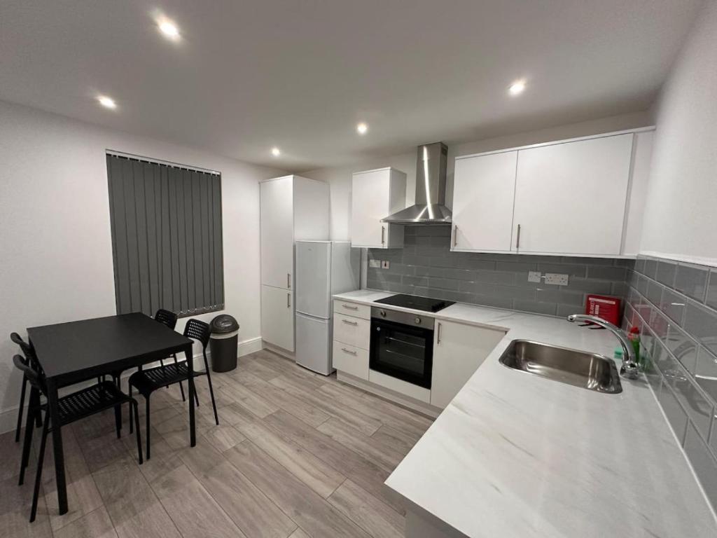 cocina con mesa y cocina con armarios blancos en Modern Central London Room Zone1, en Londres