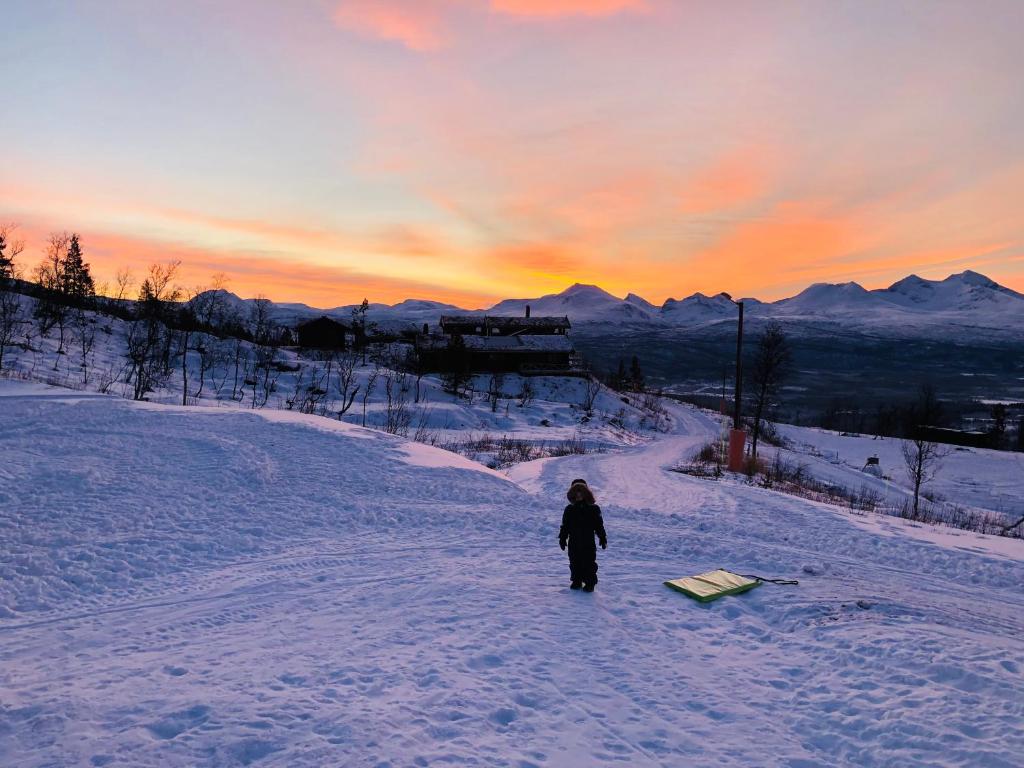 a person standing in the snow with a sled at Cabin - Målselv fjellandsby in Bergset