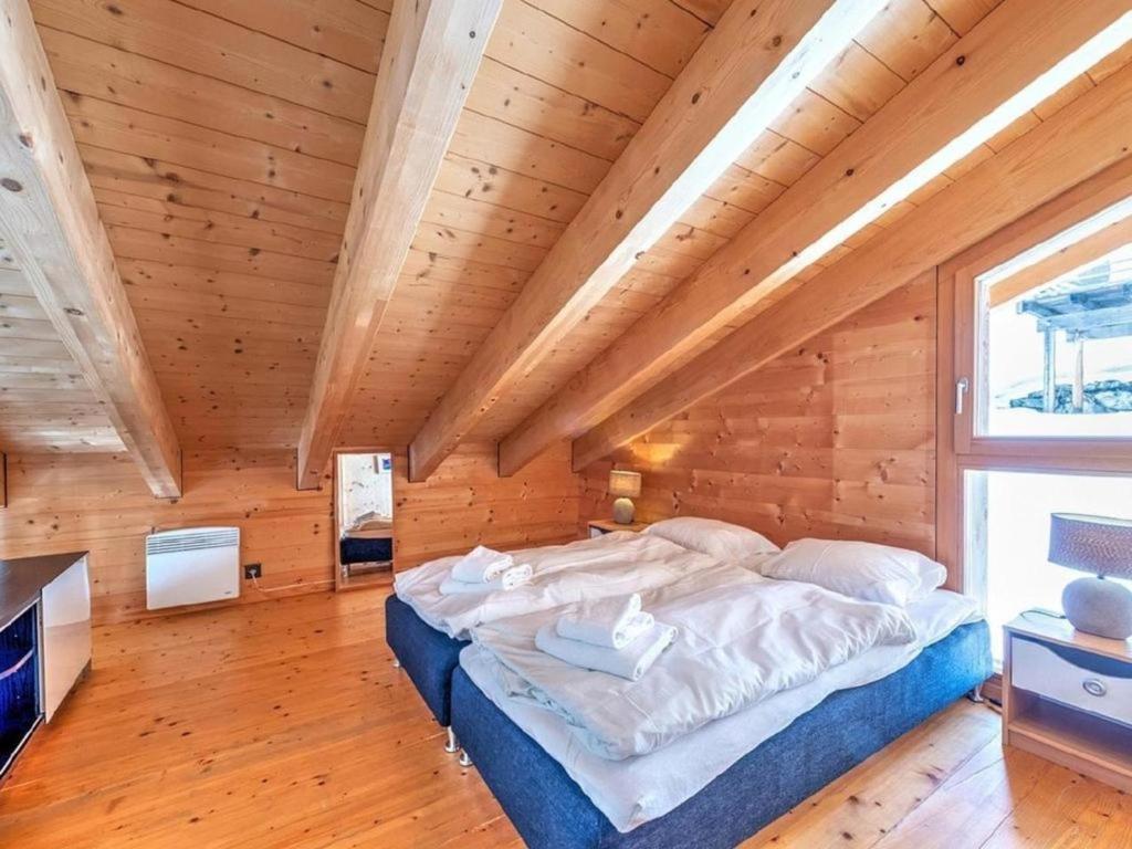 een bed in een kamer met een houten plafond bij Chalet sur Piste in Les Collons