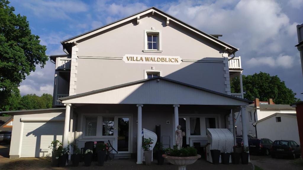 a white building with a sign on it at Villa Waldblick in Baabe