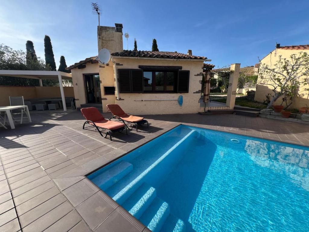 a swimming pool with two chairs and a house at Villa Franca privat pool in L'Estartit