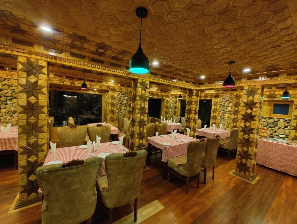a restaurant with tables and chairs in a room at Hotel Gulmarg Lux Shanum in Gulmarg