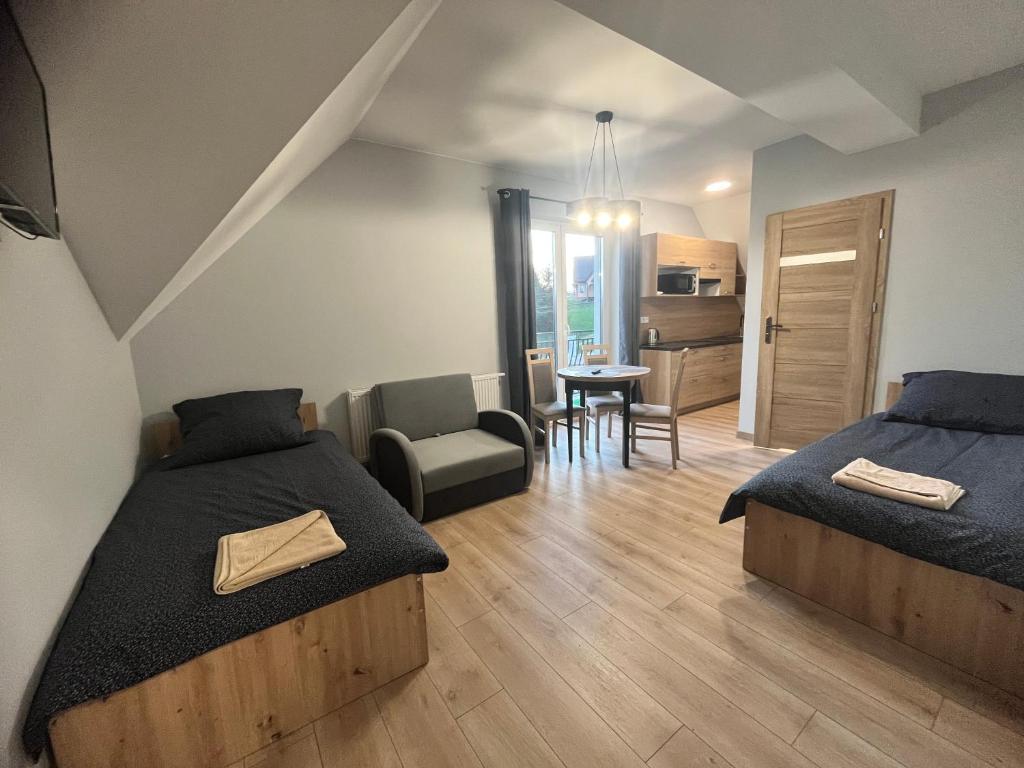 sypialnia z 2 łóżkami, krzesłem i stołem w obiekcie Apartamenty Na Rozstaju w Kluszkowcach