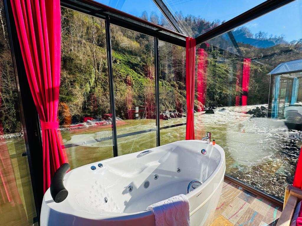 a bath tub in a room with a large window at River Land Rize in Ayder Yaylasi
