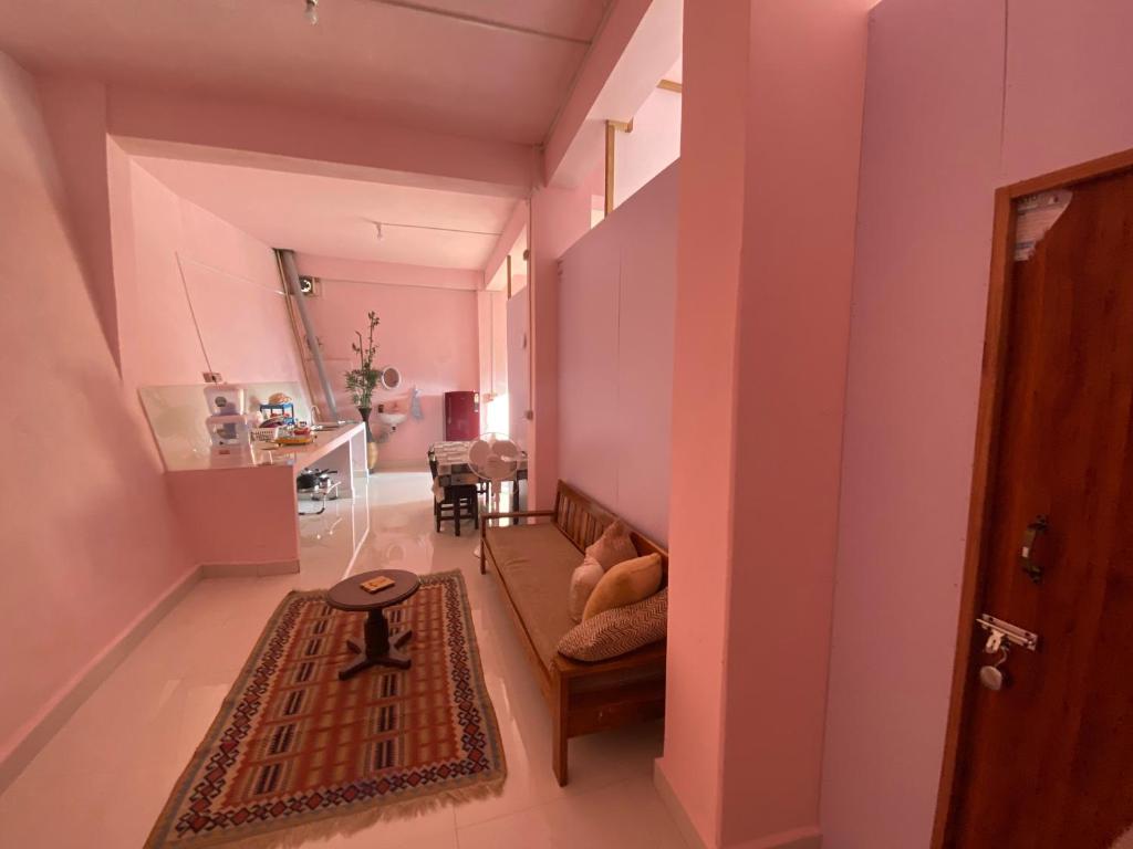 Habitación con paredes rosas, sofá y mesa. en Aizawl Homestay en Āīzawl