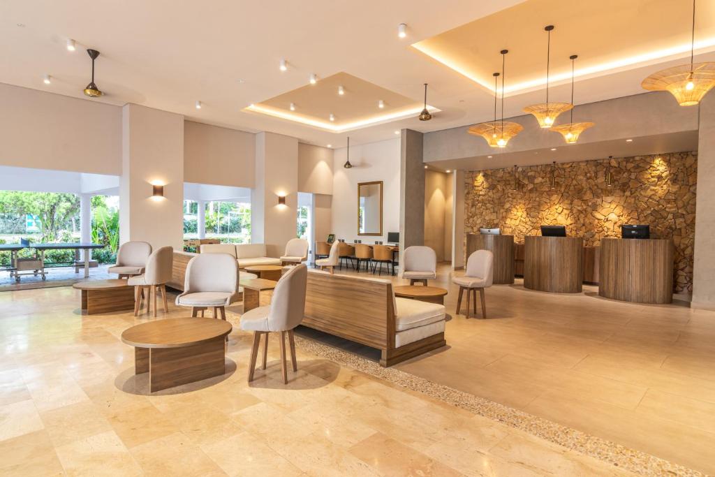 a lobby with chairs and tables and a fireplace at GHL Hotel Club el Puente in Girardot