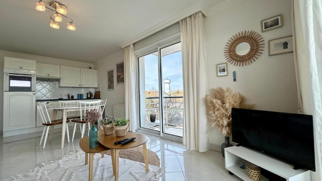 ein Wohnzimmer mit einem Flachbild-TV und einem Tisch in der Unterkunft Pointe de Sel, appartement face au port du Crotoy in Le Crotoy