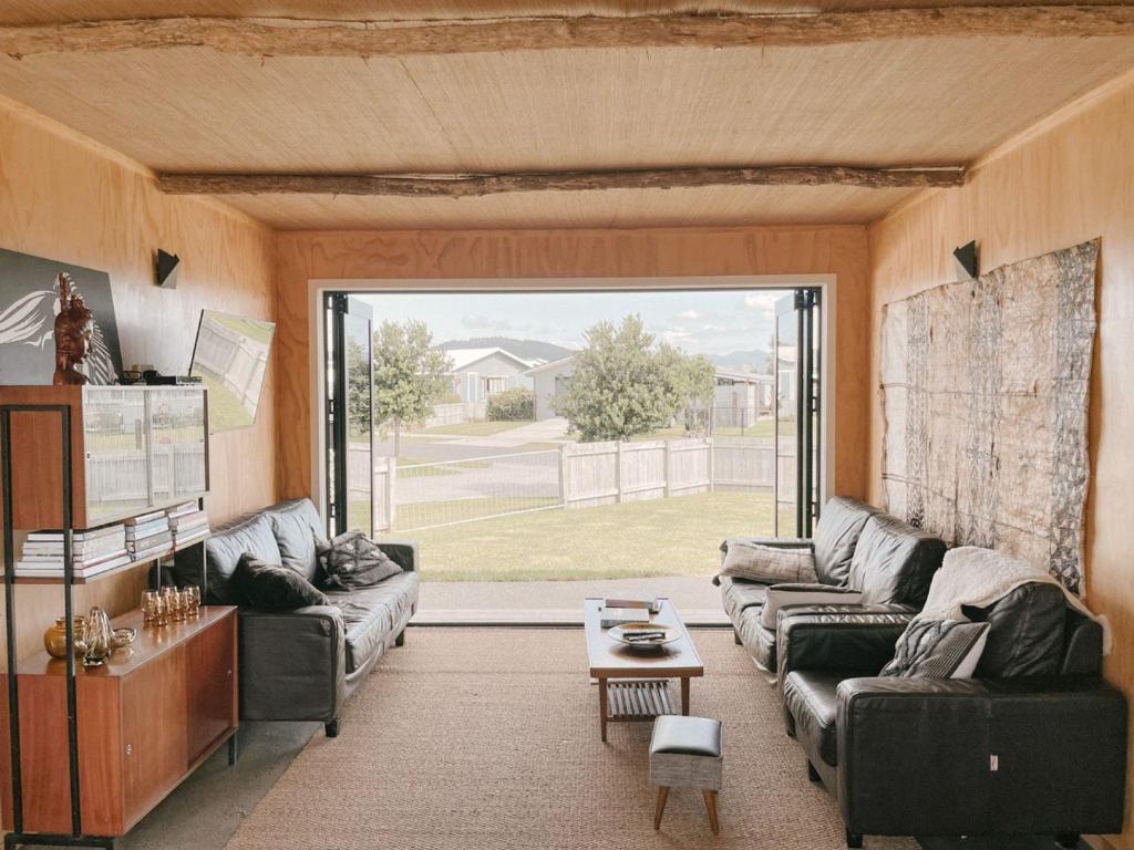sala de estar con sofás y ventana grande en Retro Style Beach Retreat - Matarangi Holiday Unit, en Matarangi