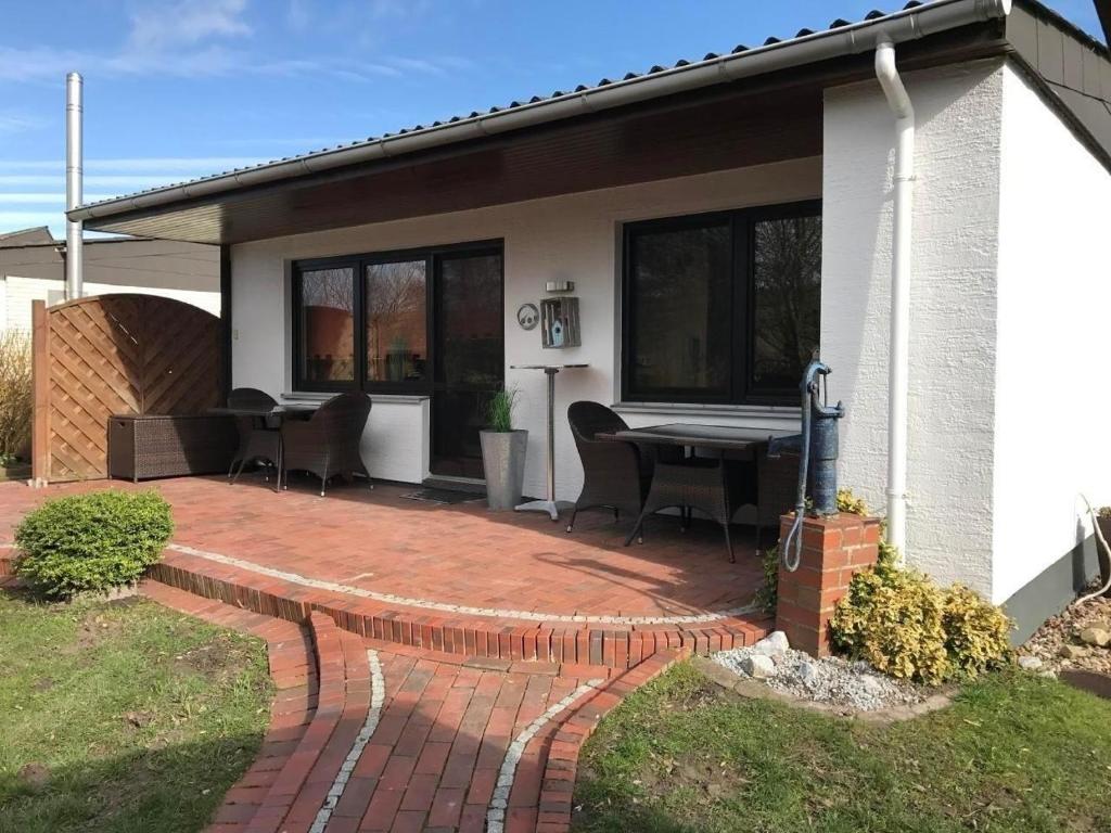 布特亚丁根E13 Ferienhaus mit Garten, Terrasse und Deichblick的房屋前设有带桌椅的天井。