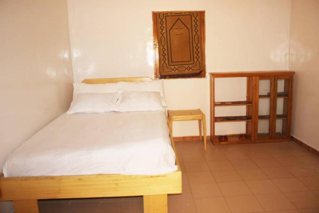 a bedroom with a bed and a wooden cabinet at Moyite Gandiol in Ndiébène