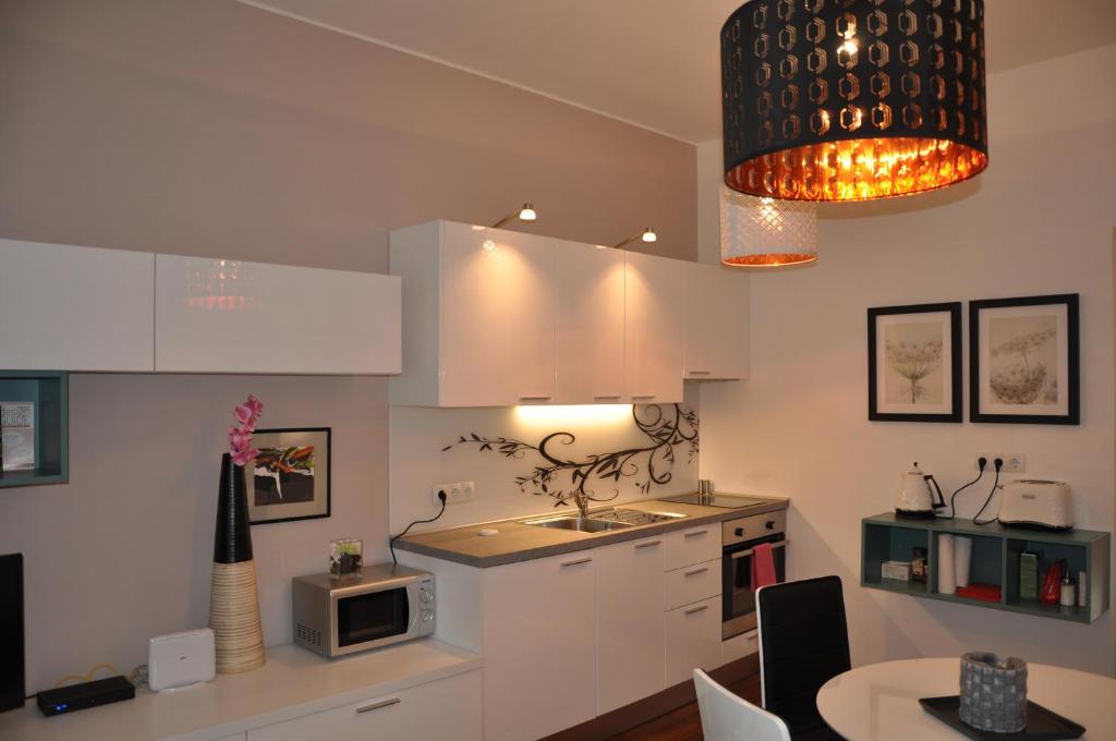 a kitchen with white cabinets and a table with a microwave at Apartments Sulekova in Zagreb