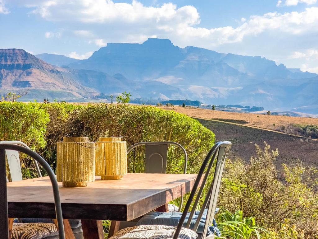 einen Holztisch und Stühle mit Bergen im Hintergrund in der Unterkunft Shiloh Cottage in Champagne Valley