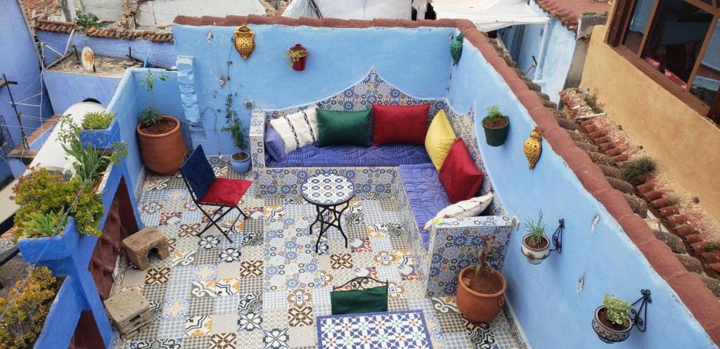 a balcony with a couch and a table and potted plants at Casa Azul in Chefchaouene