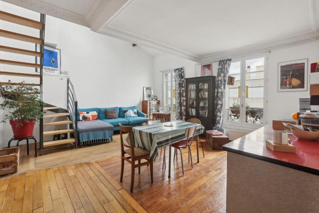 un salon avec une table et un canapé bleu dans l'établissement L'Atypique - Charmant Duplex au coeur du 20eme, à Paris