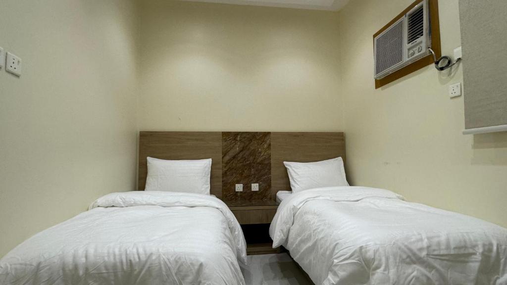 two beds in a room with white sheets at دانه القحطاني للوحدات السكنية in Tabuk