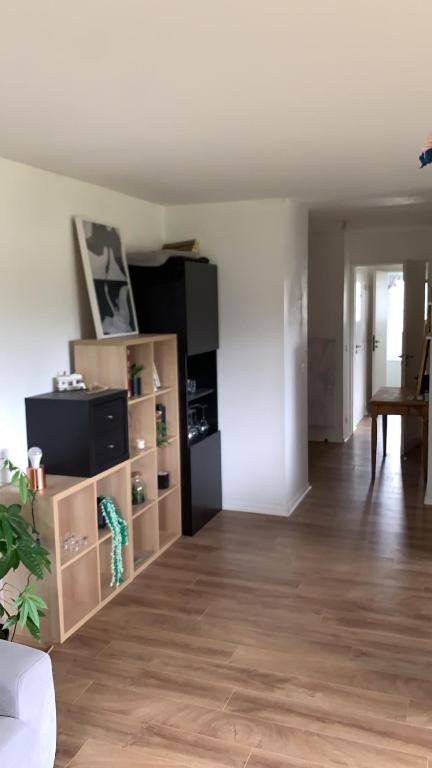a living room with a wooden floor and a black refrigerator at Appartement lumineux de 60m2 in Guer