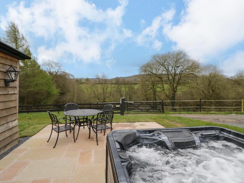 a hot tub with a table and chairs on a patio at Goldthorne Lodge in Kidderminster