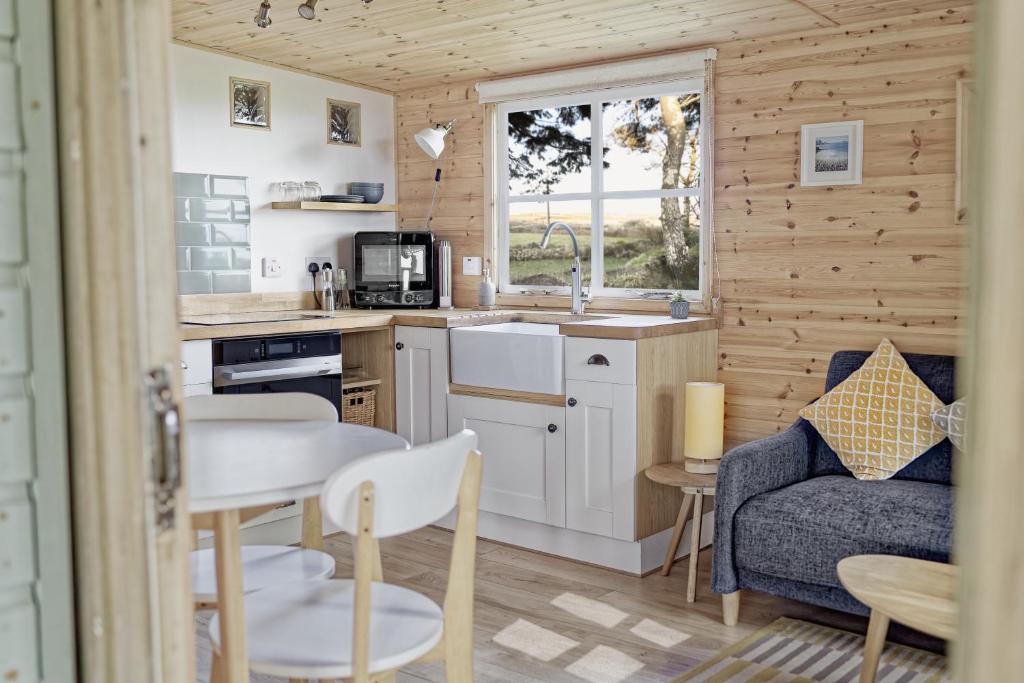 a kitchen and living room with a table and a couch at Scandi Cabin On A Hill, With Stunning Views Across Cornwall in Nancledra