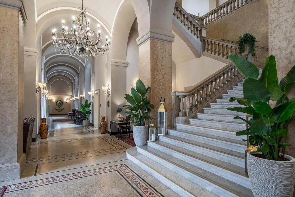 un escalier dans un bâtiment avec des plantes en pot dans l'établissement Grand Hotel di Parma, à Parme
