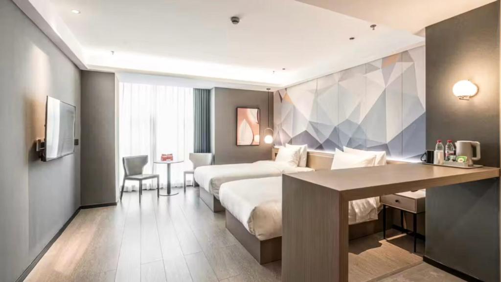 a hotel room with two beds and a desk at Veegle By Landison Ningbo in Ningbo