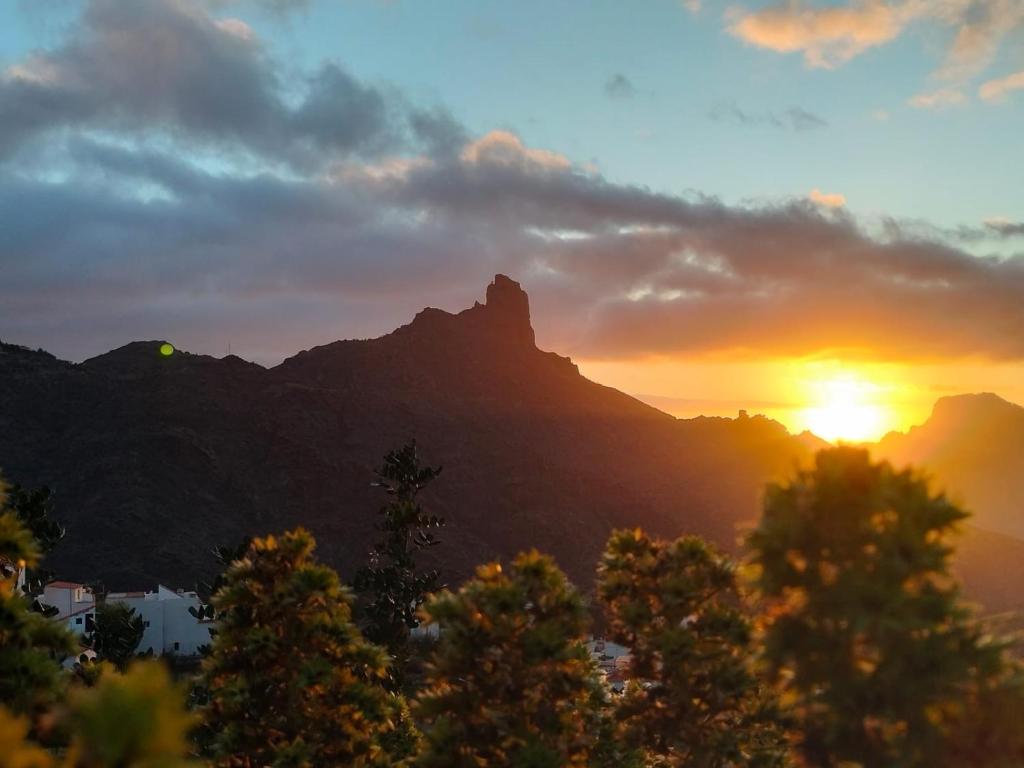 einen Sonnenuntergang in den Bergen mit Bäumen im Vordergrund in der Unterkunft El rincón de Cornelia en Tejeda in Tejeda