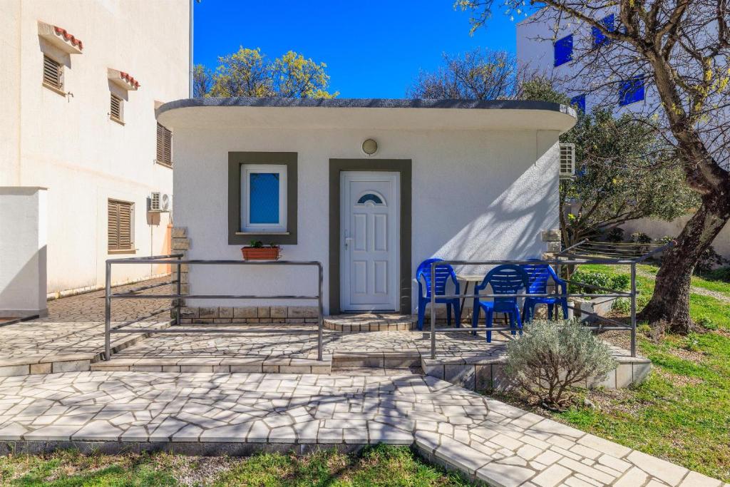 a small white house with blue chairs in front of it at Apartment Julija in Povile