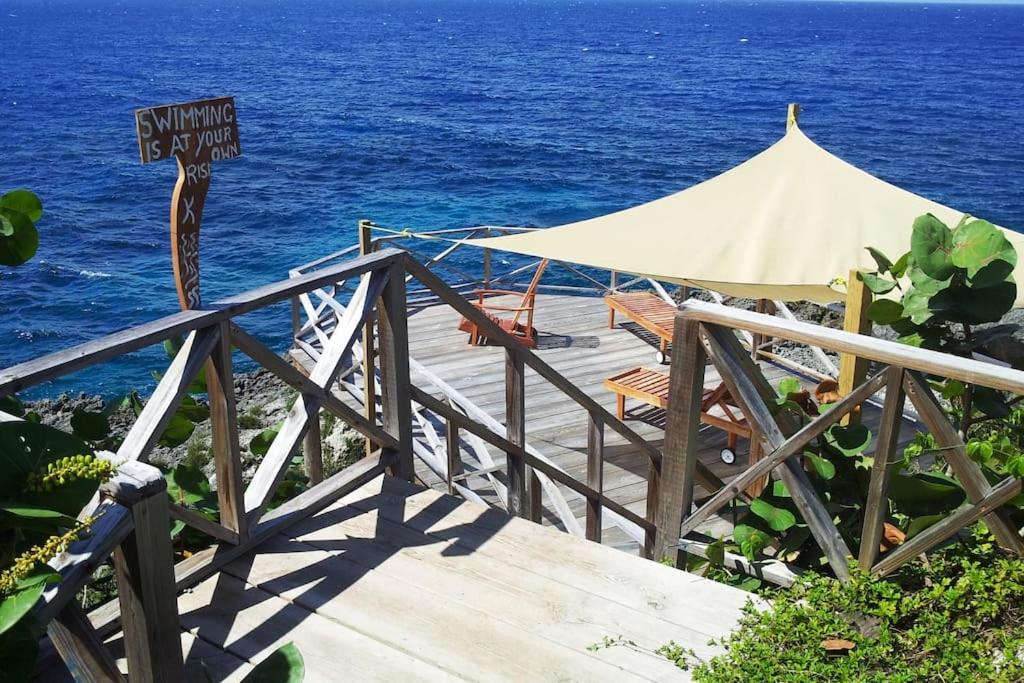 a wooden boardwalk with a tent and the ocean at Real Jamaica - Cabin right beside the sea-Papa Curvins Yard in Oracabessa